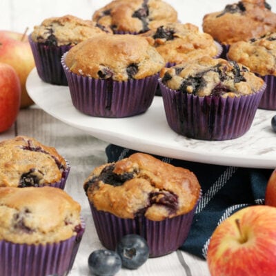 blueberry and apple muffins with apples and blueberries scattered around.