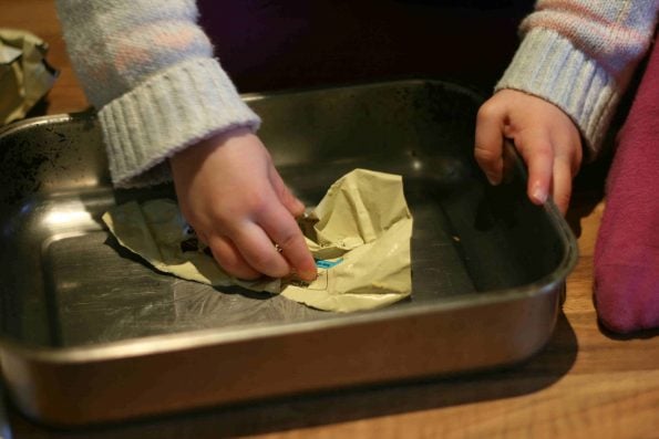 child buttering a baking tin.