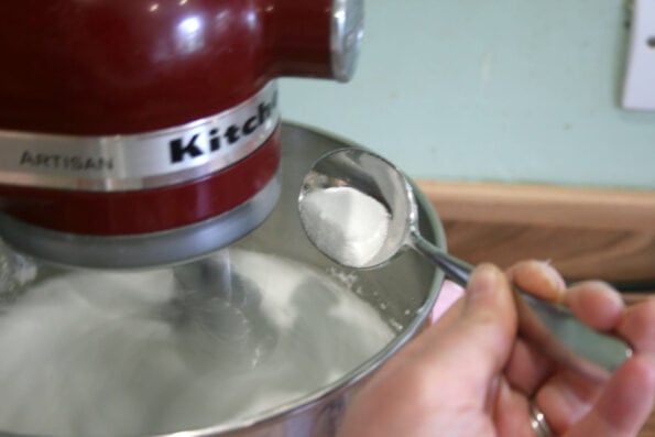 Adding a teaspoon of caster sugar to a stand mixer.