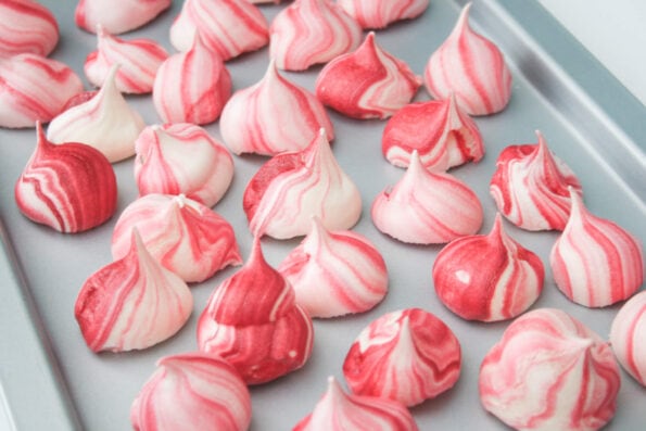 Meringue kisses on a baking tray.