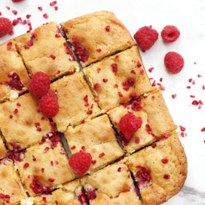 raspberry and white chocolate blondies on a white serving plate
