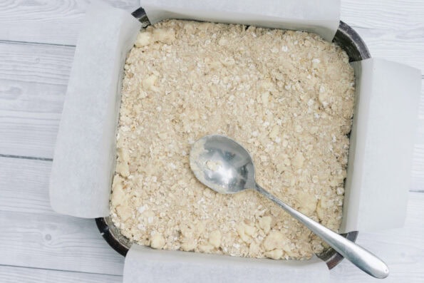 pressing an oatmeal crumb into a baking tin.