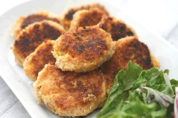 sweet potato fish cakes on a white plate with salad.