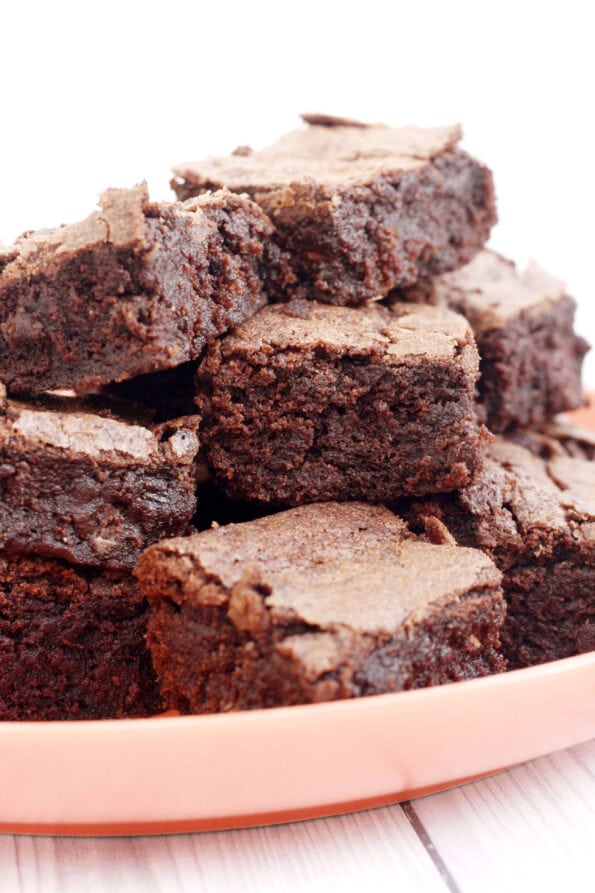 Chocolate brownies on an orange plate.