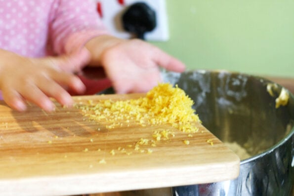 child adding lemon zest to a mixing bowl