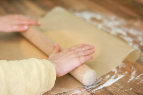 child rolling out biscuit dough.