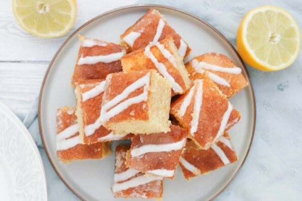 lemon drizzle traybake cut into slices on a round plate. 