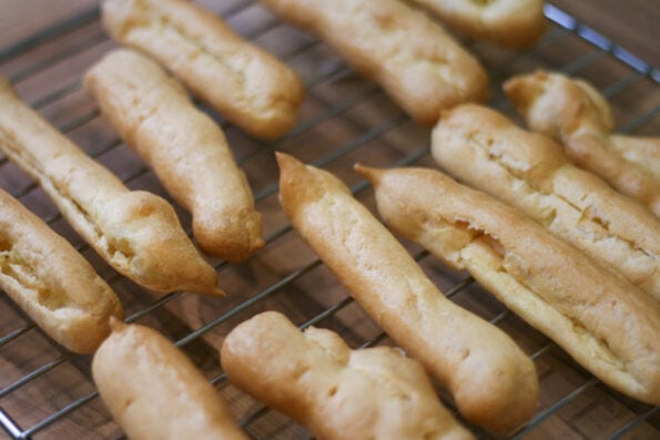 eclairs before being filled and decorated on a wire rack. 