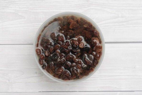 sultanas soaking in water in a bowl.
