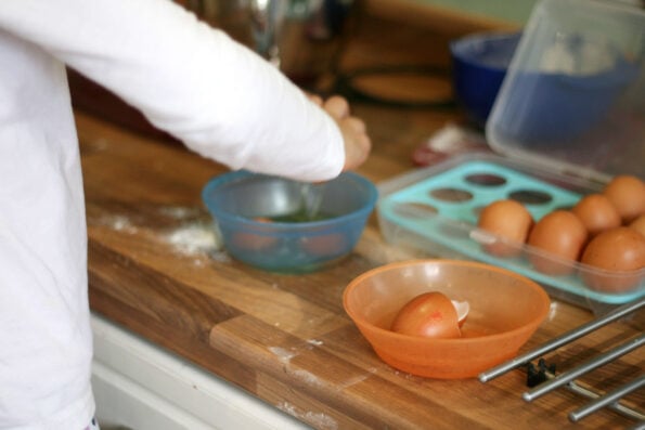 child cracking eggs into a bowl