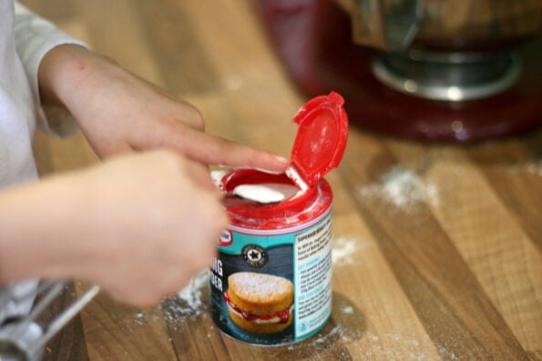 child measuring baking powder