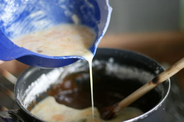 pouring whisked egg and milk into a pan