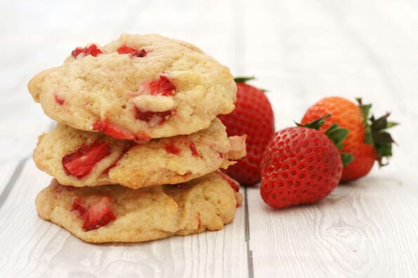 Strawberry cookies in a pile with 3 strawberries on the side