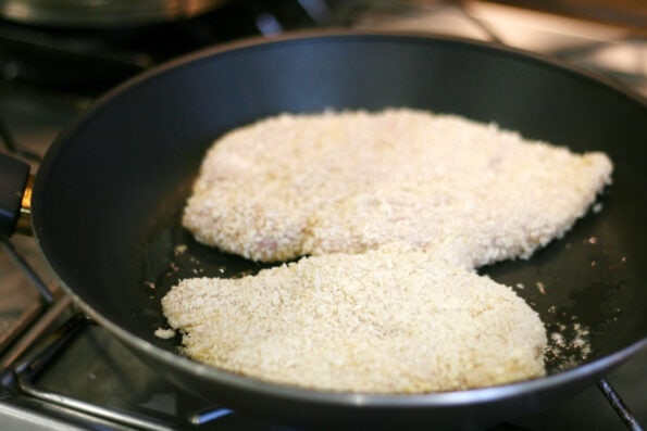 panko covered chicken breasts in a frying pan