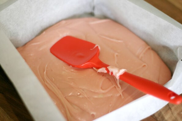 strawberry fudge in a baking tray with a red spatula