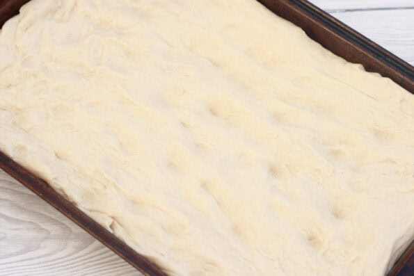 focaccia proving in a baking tray.