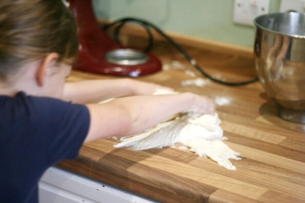 child kneading focaccia dough