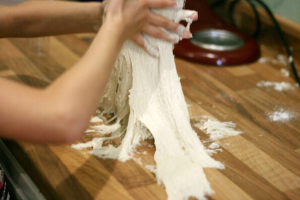 child kneading focaccia dough