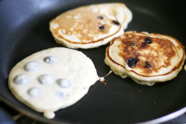 cooking blueberry pancakes in a frying pan