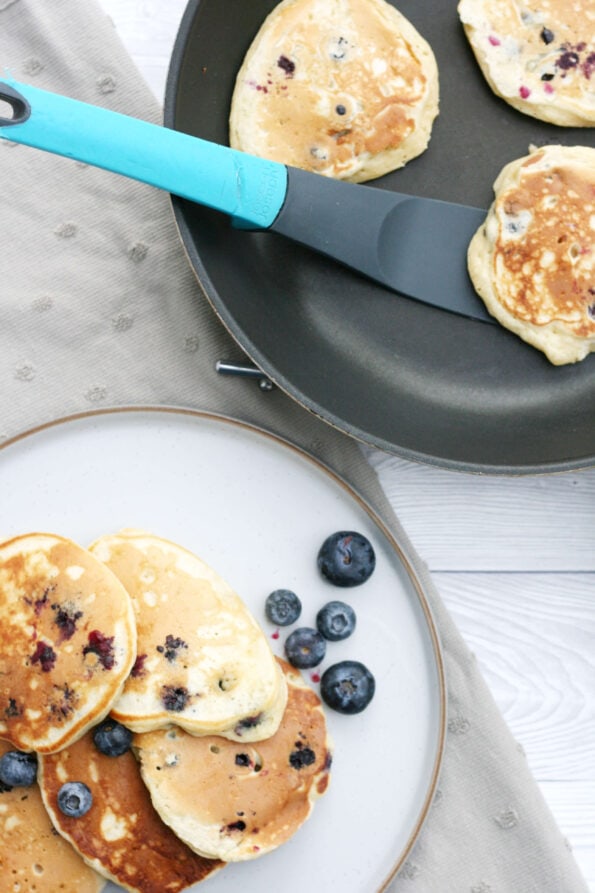 blueberry pancakes in a frying pan and serving plate