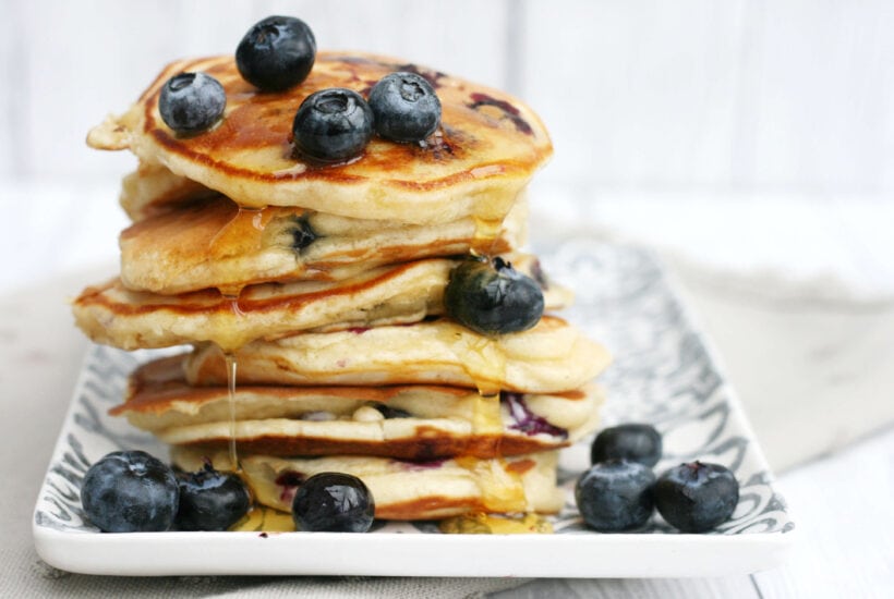blueberry pancakes in a stack with syrup on top