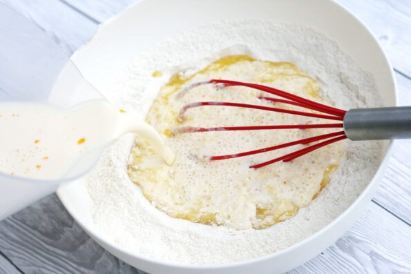 pouring milk into flour in a bowl