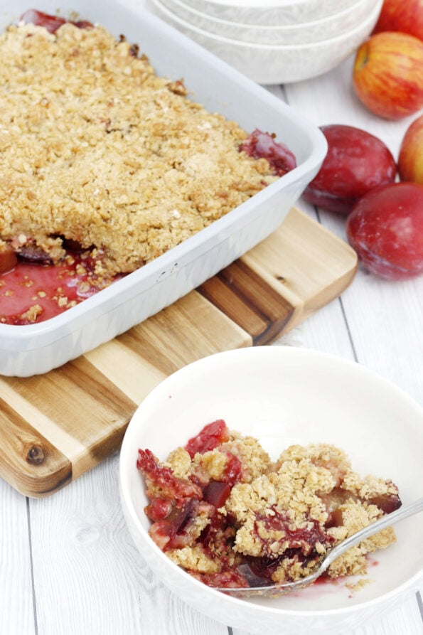 plum and apple crumble in a bowl with the dish in the background