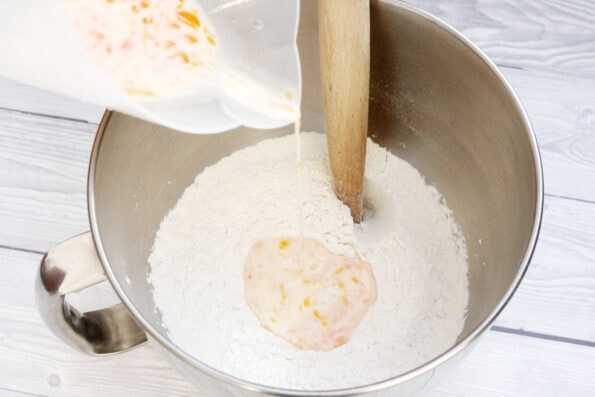 Pouring an egg and milk mixture into a bowl of flour.