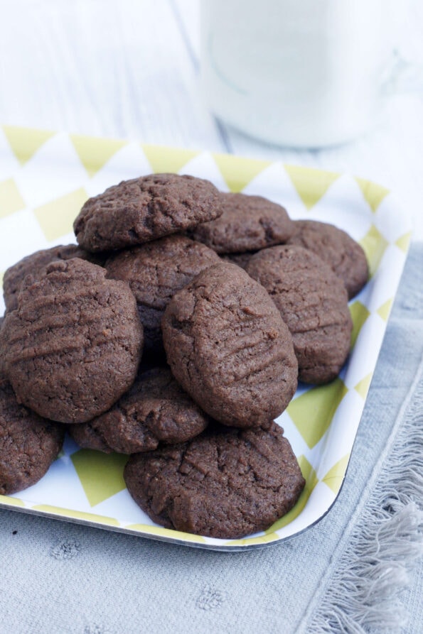 chocolate fork biscuits on a yellow serving tray with milk in the background.