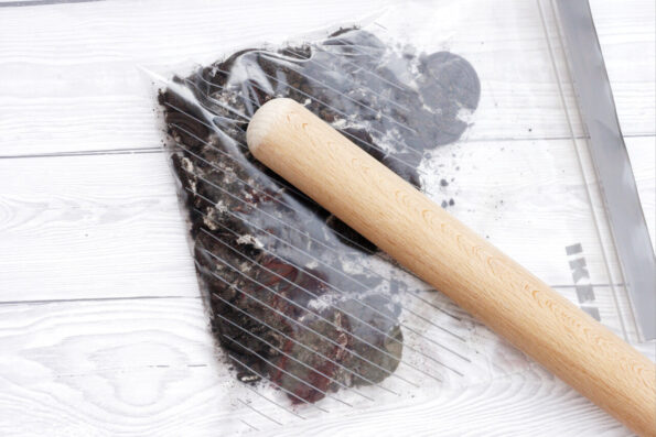 bashing chocolate biscuits in a bag to make crumbs with a rolling pin