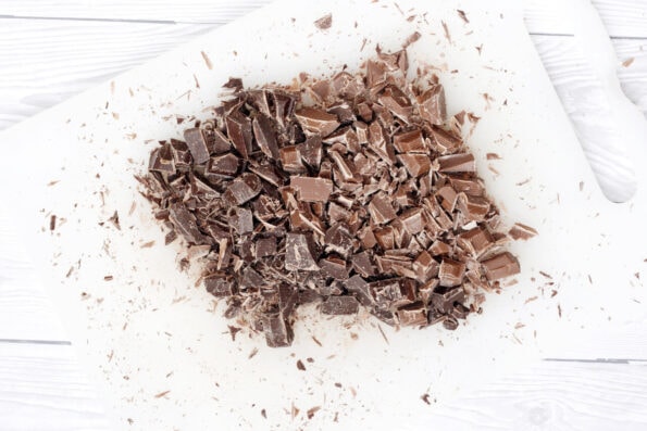 chocolate pieces cut up on a white chopping board.