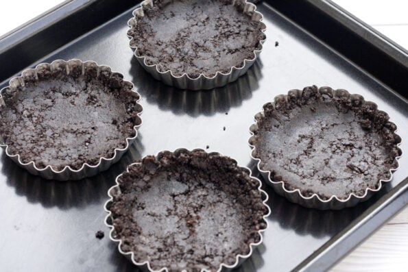 4 chocolate tart bases on a baking tray.