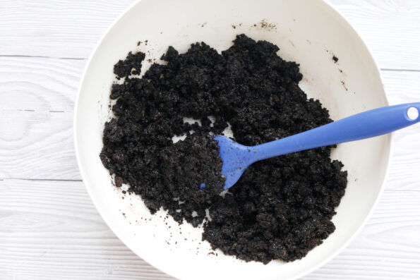 chocolate biscuit crumbs coated in butter in a bowl.