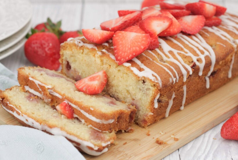 Strawberry loaf cake sliced on a wooden board.