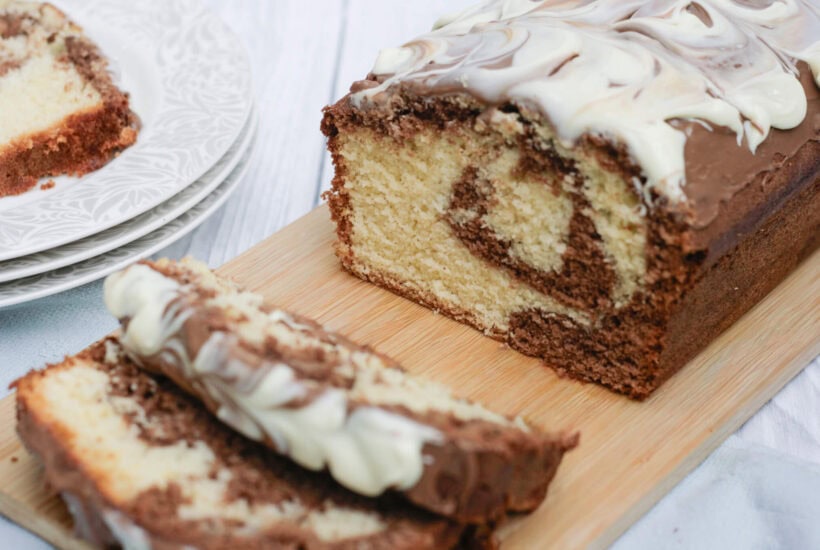 marble loaf cake cut into slices on a wooden serving board.