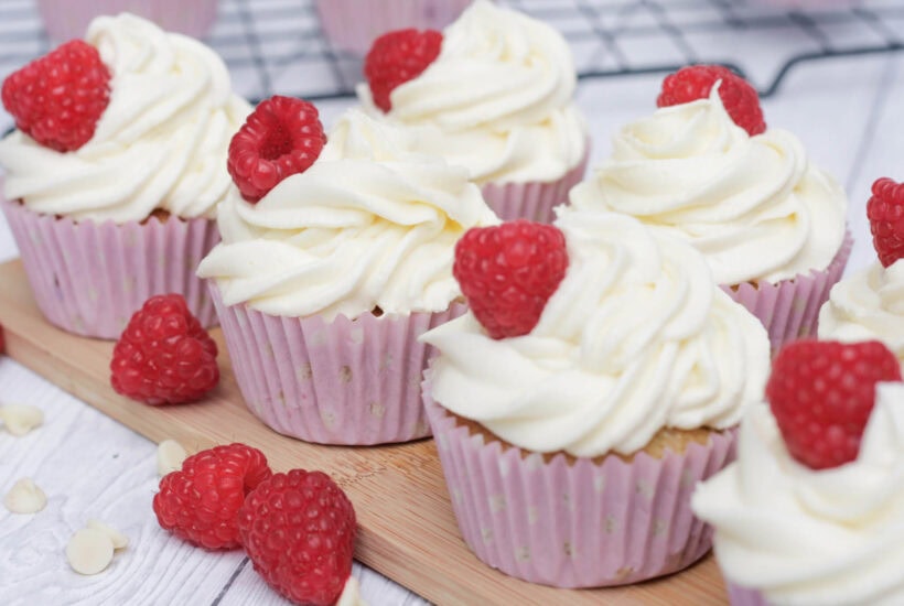 raspberry and white chocolate cupcakes on a serving board.