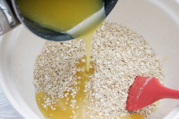 pouring melted butter into a bowl of porridge oats.