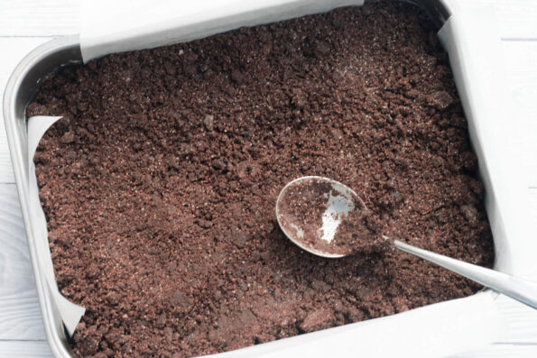 pressing chocolate crunch into a baking tin.